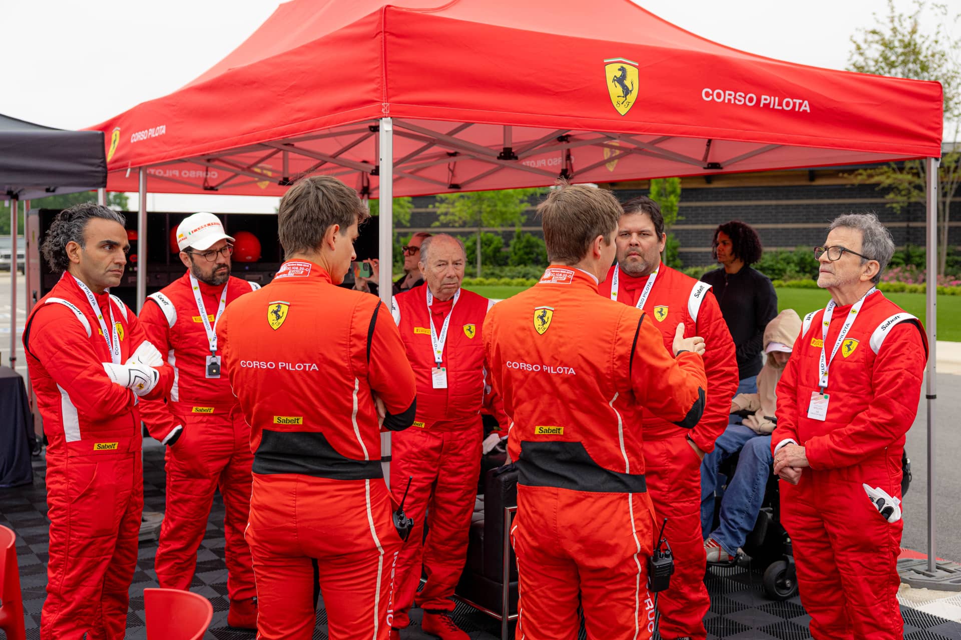 Drivers in Ferrari Corso Pilota race suits under the official red Corso Pilota tent at Ten Tenths