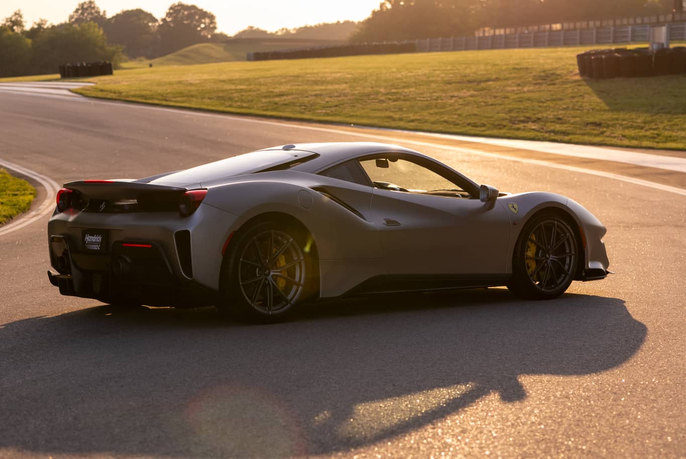 Rear angled view of a Ferrari on a racing track at sunset
