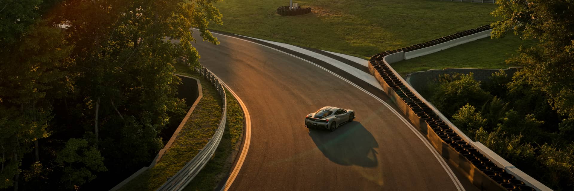 Aerial angled view from above of a Ferrari on a racing track at sunset